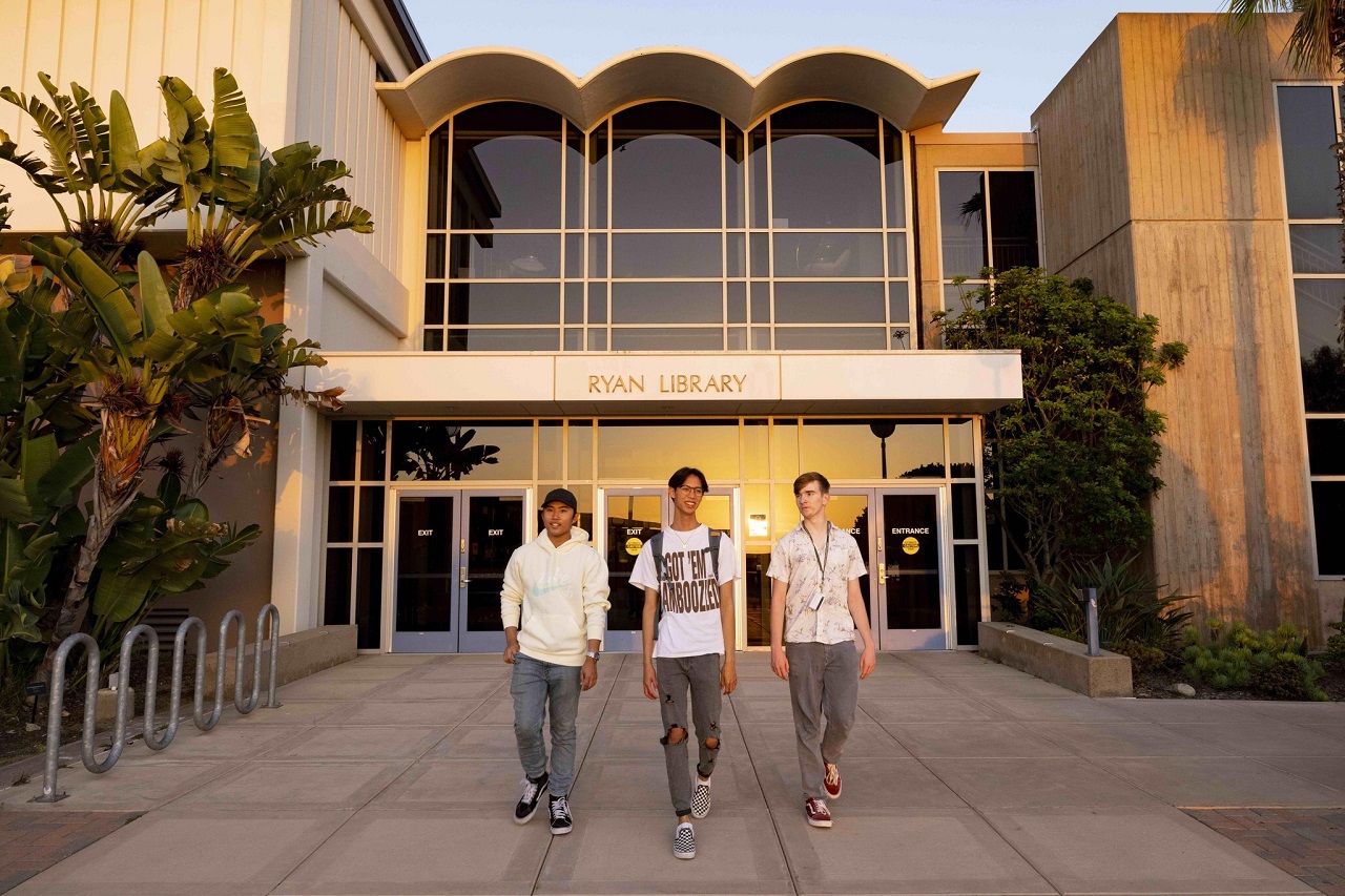Three male students walking away from Ryan Library at Point Loma Nazarene University in San Diego, California