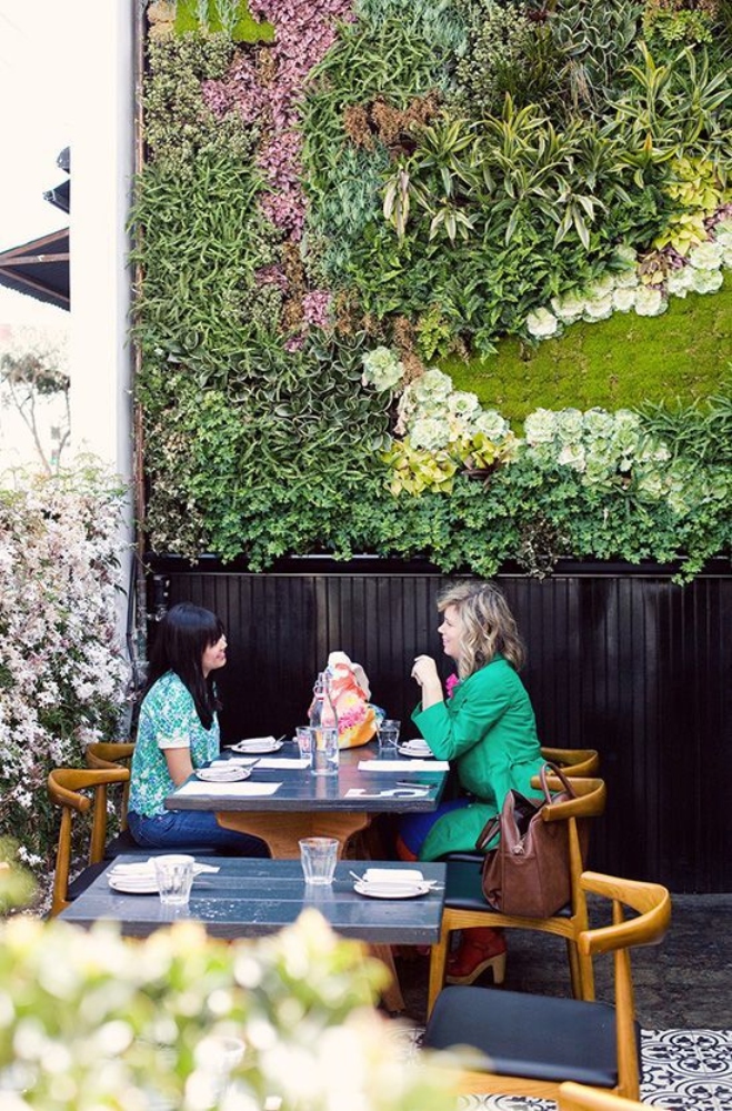 Two women sitting next to a green wall in Goldie's restaurant