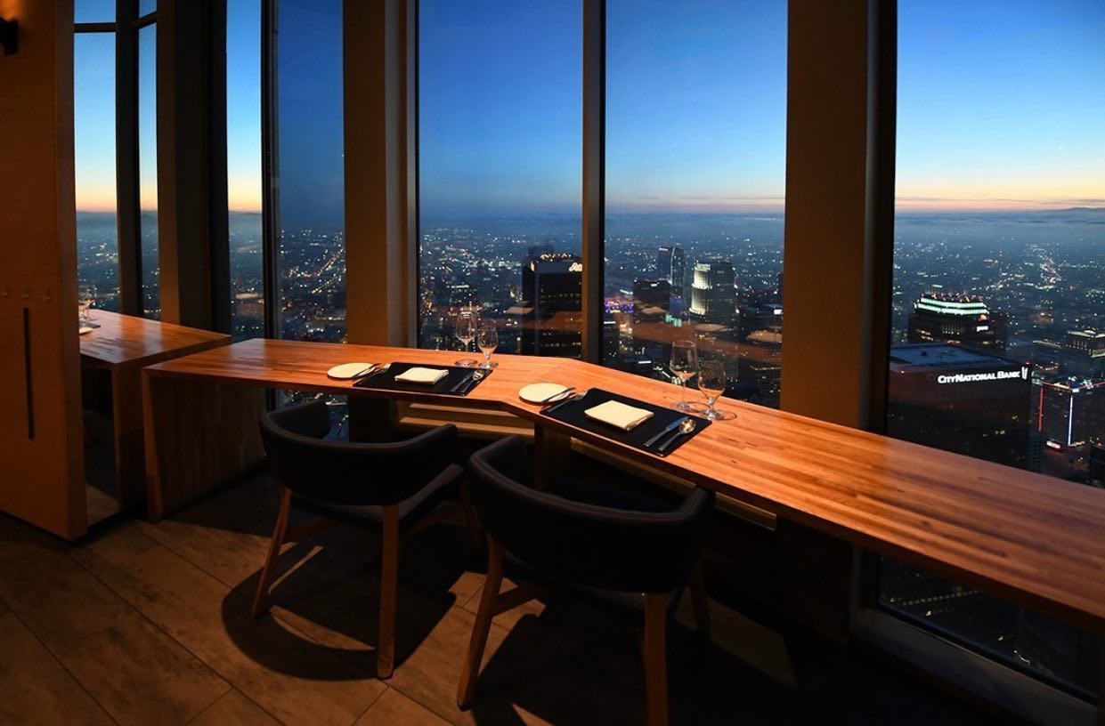 A table setting for two facing a panoramic view of the city at nighttime at 71Above in Los Angeles