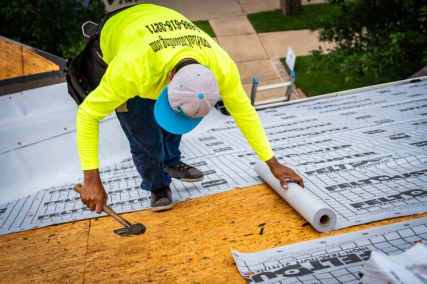A man installing synthetic roof underlayment