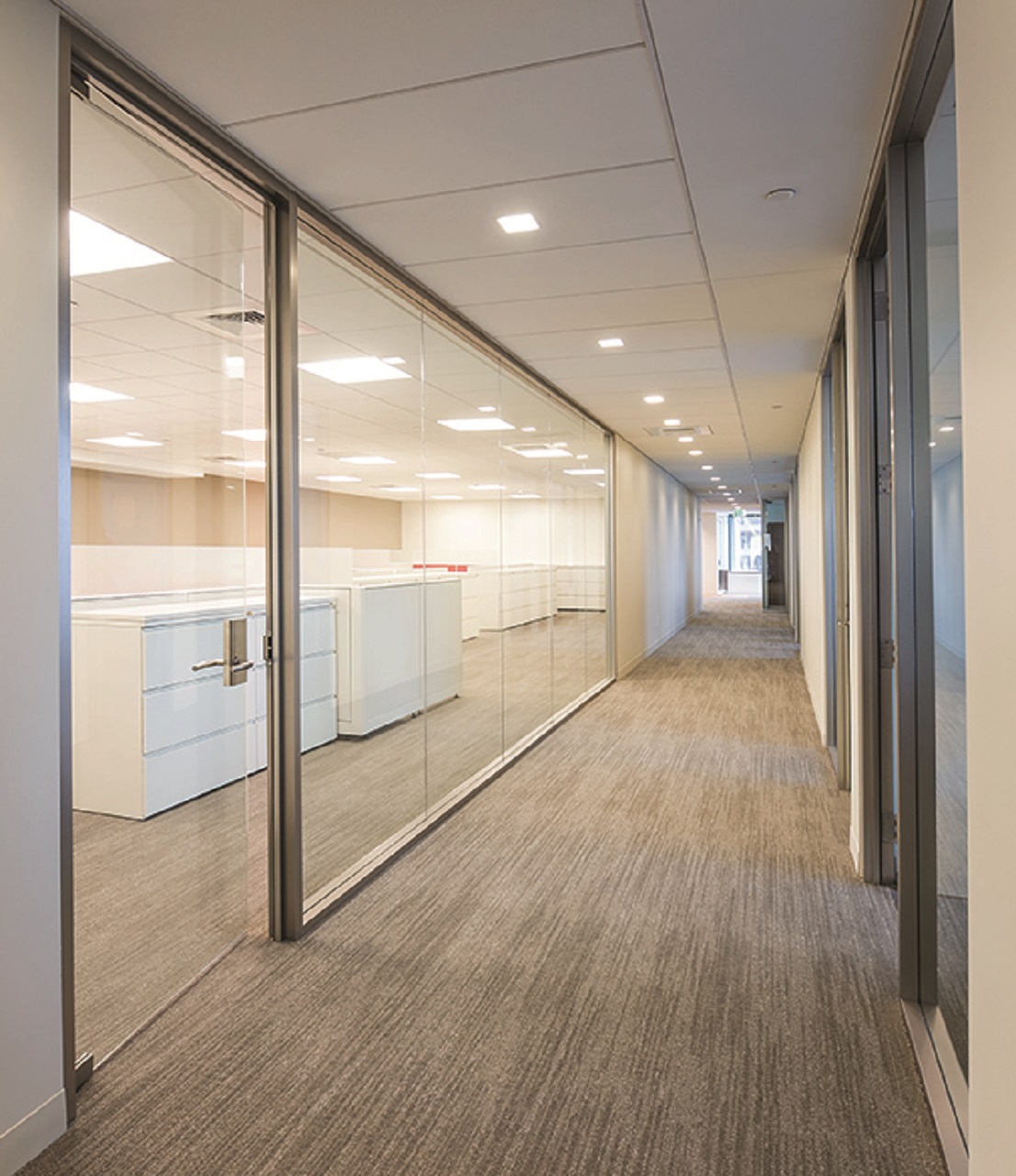 Empty office hallway of Cozen O’Connor in Pennsylvania, with a well-lit office with glass walls and door